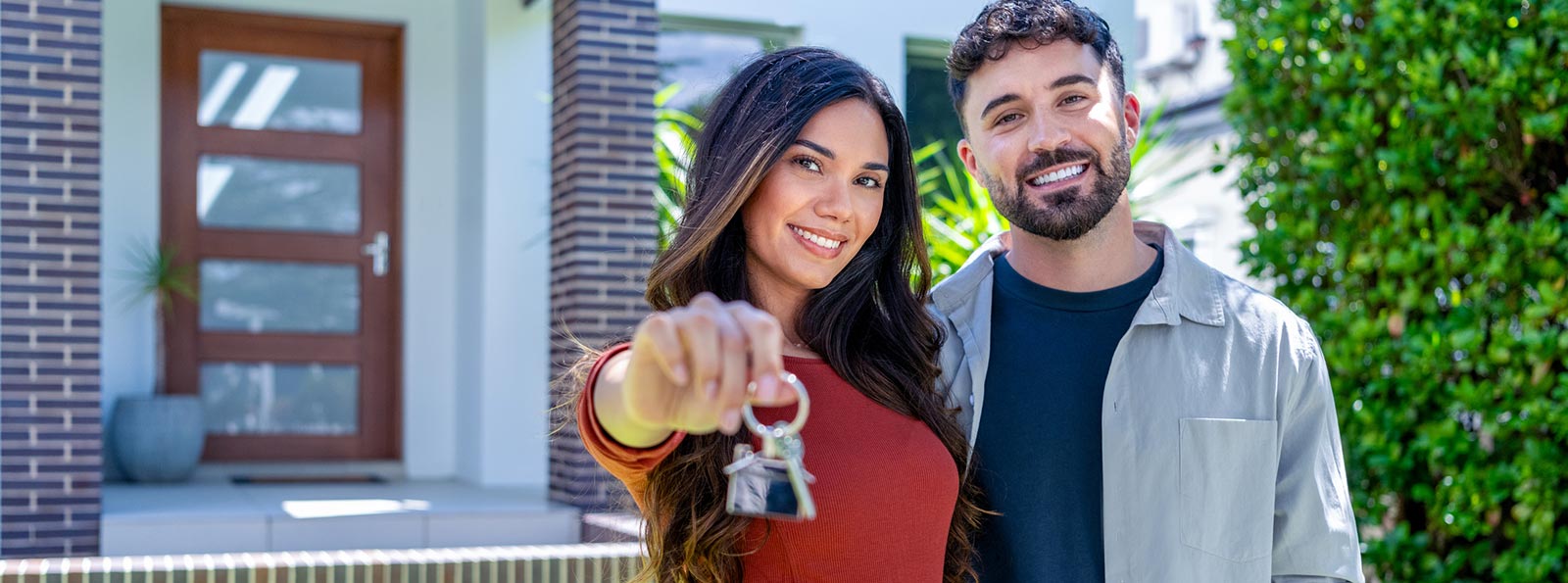 Couple holding the keys in front of their new house
